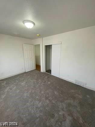 unfurnished bedroom featuring a closet and dark colored carpet