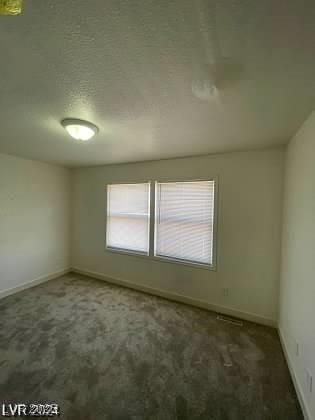 spare room featuring dark colored carpet