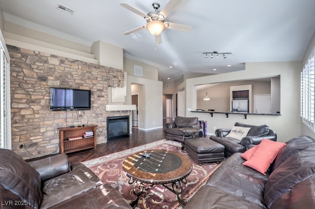 living room with lofted ceiling, ceiling fan, a stone fireplace, and hardwood / wood-style flooring