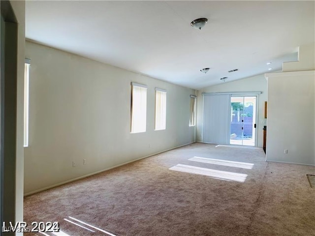 carpeted spare room with a wealth of natural light and vaulted ceiling