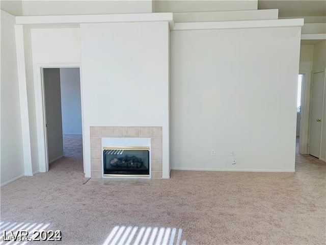 unfurnished living room with light carpet and a tile fireplace