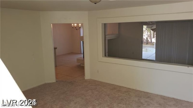 spare room featuring carpet and an inviting chandelier