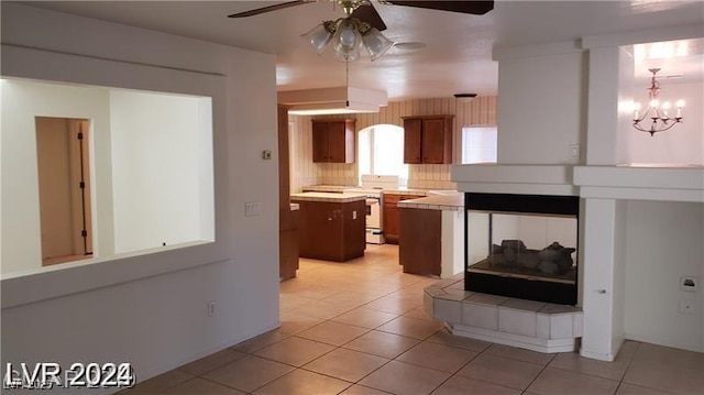 kitchen with decorative backsplash, light tile patterned floors, a center island, and ceiling fan with notable chandelier