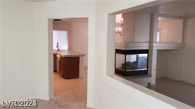 corridor featuring a chandelier, light tile patterned floors, and sink