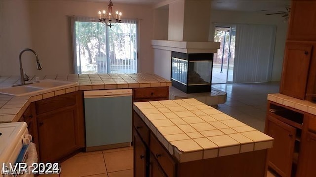 kitchen featuring sink, decorative light fixtures, dishwasher, a center island, and tile counters