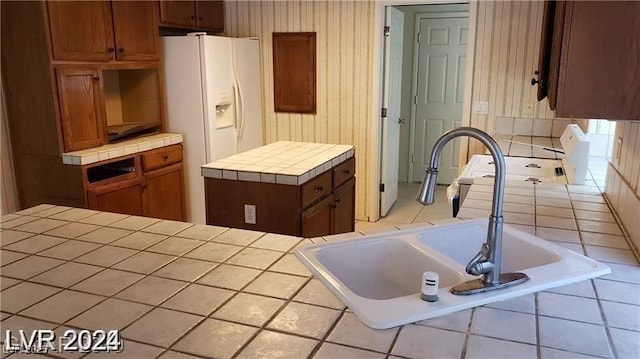 kitchen featuring tile countertops, sink, and white refrigerator with ice dispenser