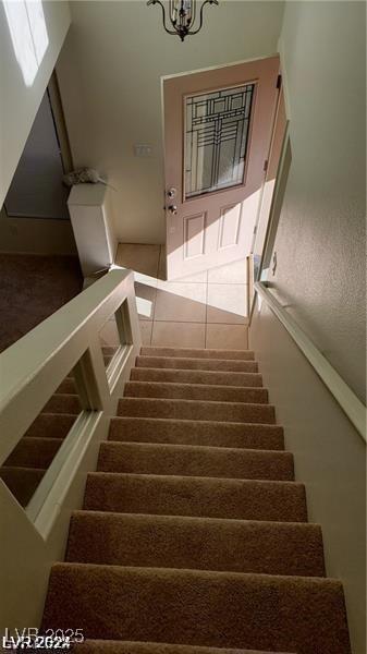 stairs featuring tile patterned floors and an inviting chandelier