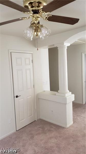 spare room with decorative columns, ceiling fan, and light colored carpet