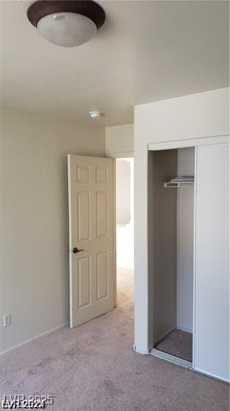 unfurnished bedroom with light colored carpet and a closet