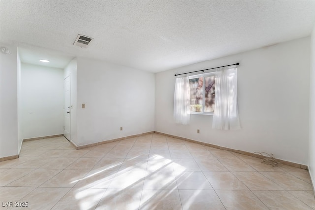 spare room featuring light tile patterned floors and a textured ceiling