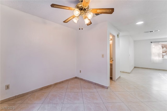 tiled empty room with ceiling fan and a textured ceiling