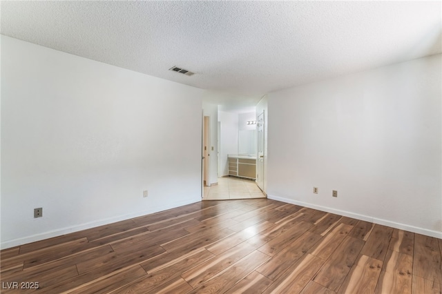 spare room featuring hardwood / wood-style flooring and a textured ceiling