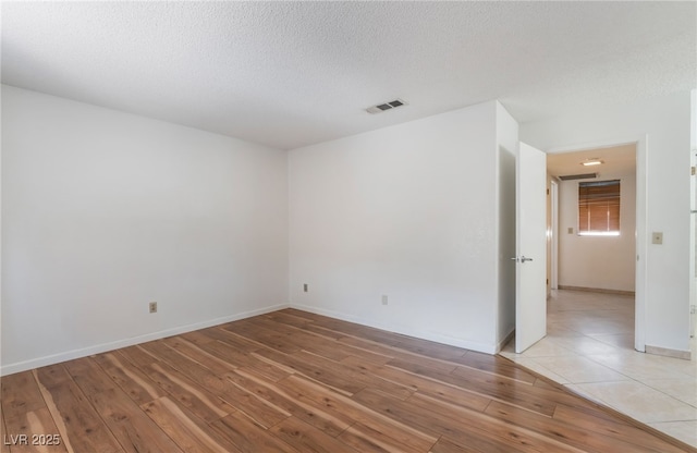 spare room with light hardwood / wood-style floors and a textured ceiling