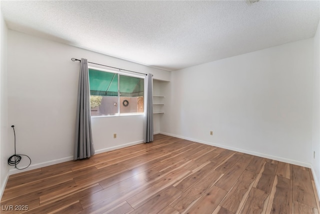 empty room featuring wood-type flooring and a textured ceiling