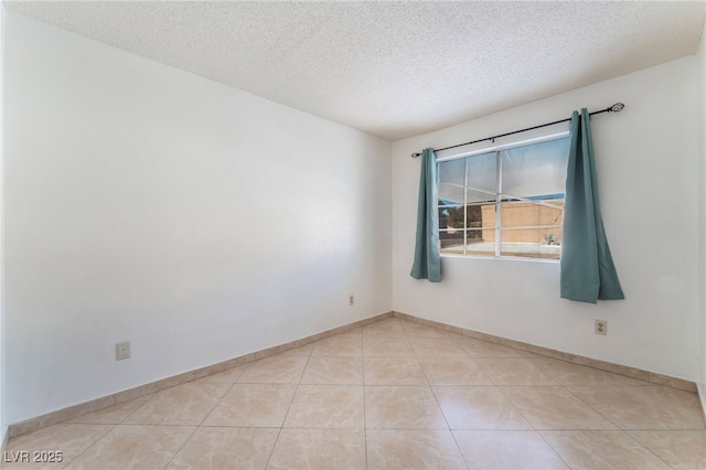 tiled empty room featuring a textured ceiling