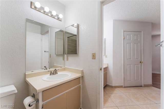 bathroom featuring tile patterned flooring, vanity, a textured ceiling, and toilet