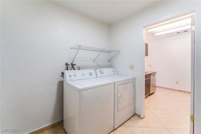 laundry area with light tile patterned floors and washing machine and clothes dryer