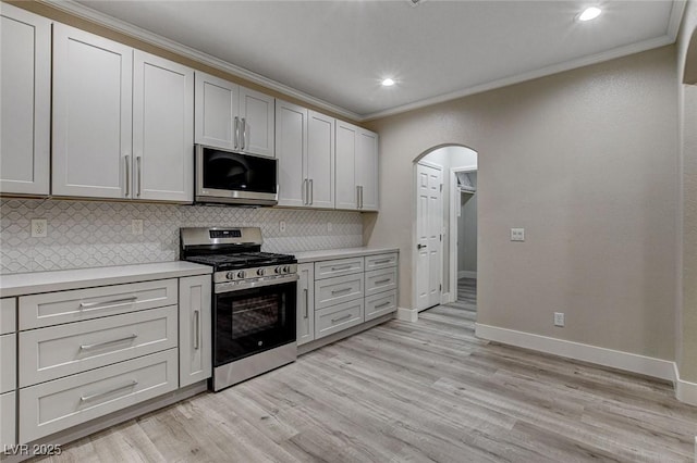 kitchen featuring decorative backsplash, ornamental molding, stainless steel appliances, light hardwood / wood-style flooring, and white cabinets