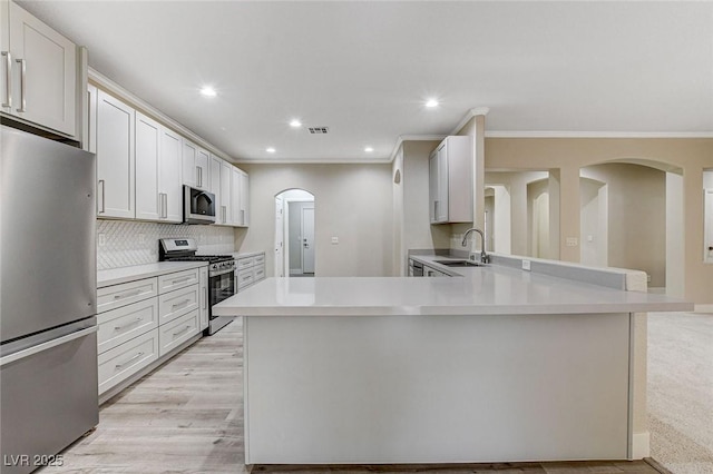 kitchen with kitchen peninsula, white cabinetry, sink, and appliances with stainless steel finishes