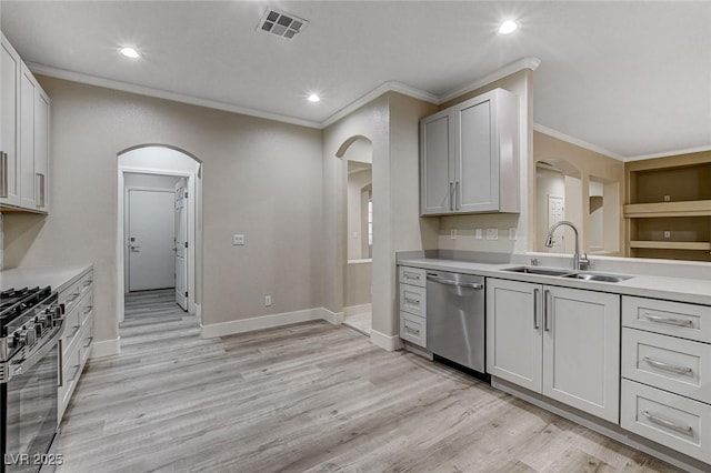 kitchen with light wood-type flooring, stainless steel appliances, crown molding, sink, and white cabinetry