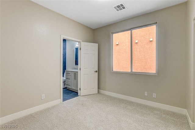 unfurnished bedroom featuring connected bathroom, carpet, and multiple windows