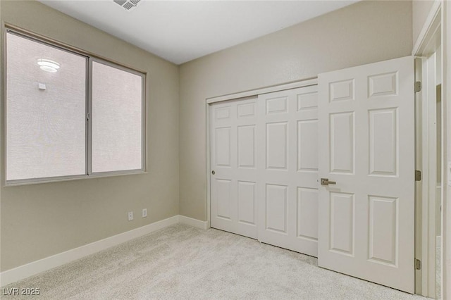 unfurnished bedroom with light colored carpet and a closet