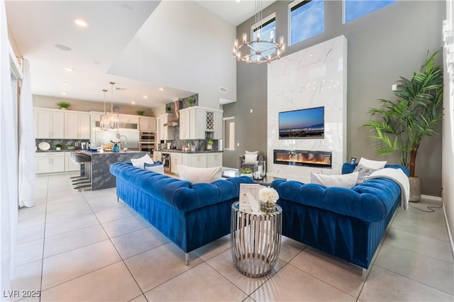 tiled living room with a towering ceiling, a fireplace, and a chandelier