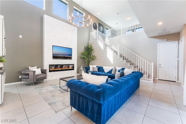 tiled living room featuring a high end fireplace, a high ceiling, and a notable chandelier