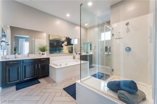 bathroom featuring plus walk in shower, a healthy amount of sunlight, and vanity