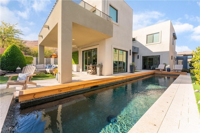 back of property featuring a balcony, ceiling fan, an outdoor living space, and a patio