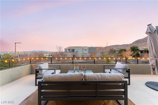 patio terrace at dusk with a balcony, outdoor lounge area, and a mountain view