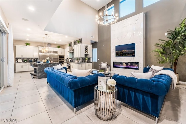 tiled living room featuring a towering ceiling and an inviting chandelier