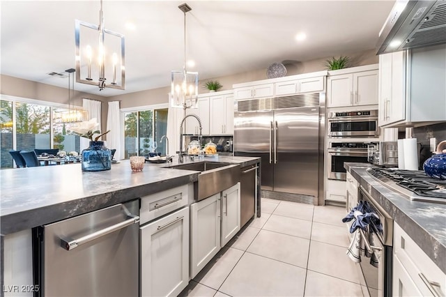 kitchen with sink, appliances with stainless steel finishes, white cabinetry, and hanging light fixtures