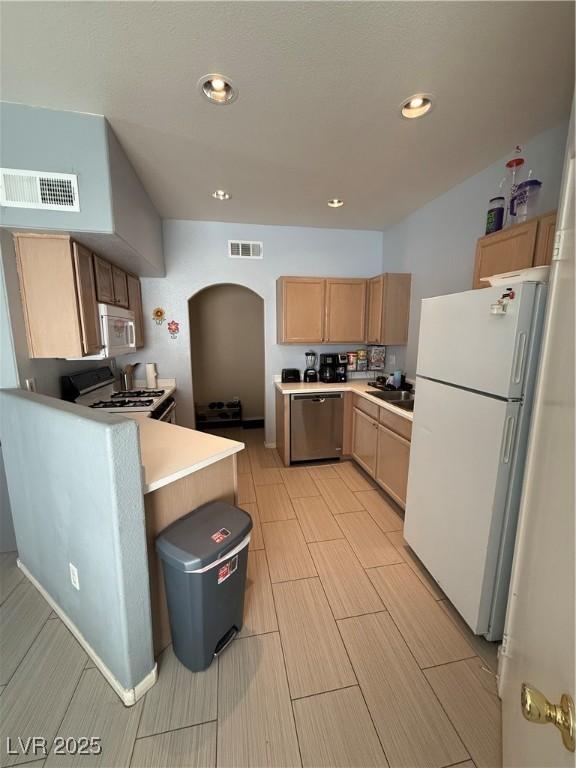 kitchen featuring stove, stainless steel dishwasher, sink, light brown cabinets, and white fridge