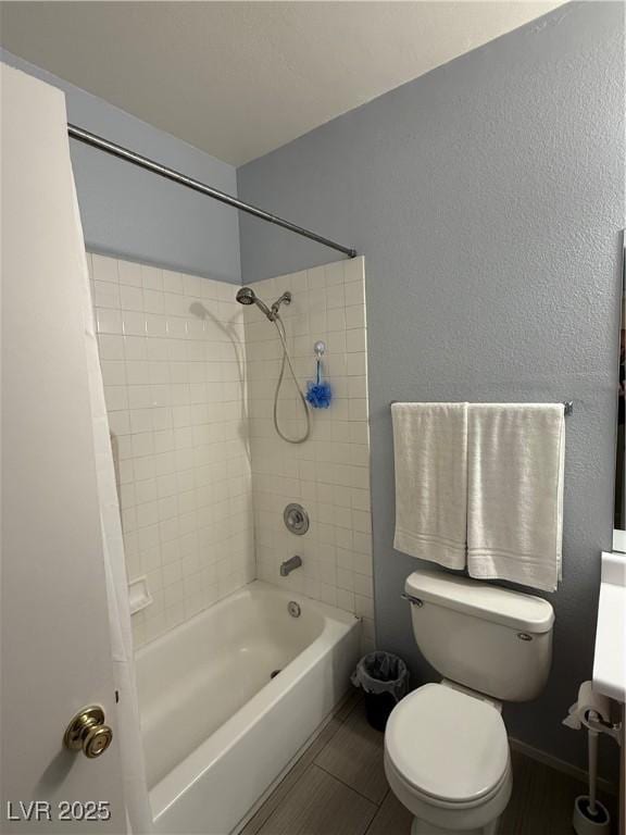 bathroom featuring tile patterned floors, toilet, and tiled shower / bath