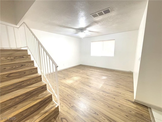 empty room featuring ceiling fan, hardwood / wood-style floors, and a textured ceiling