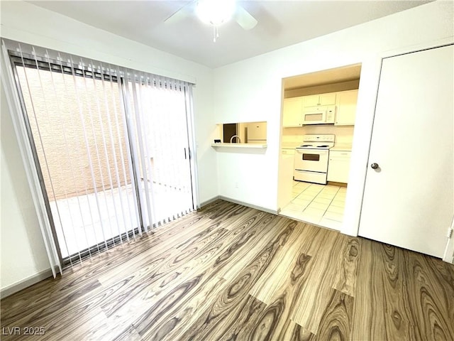 interior space featuring white cabinets, light wood-type flooring, white appliances, and a wealth of natural light