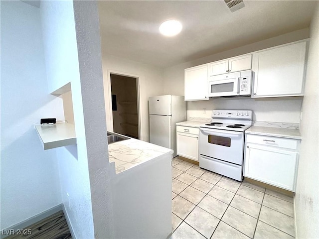 kitchen featuring light stone countertops, light tile patterned floors, white appliances, and white cabinetry