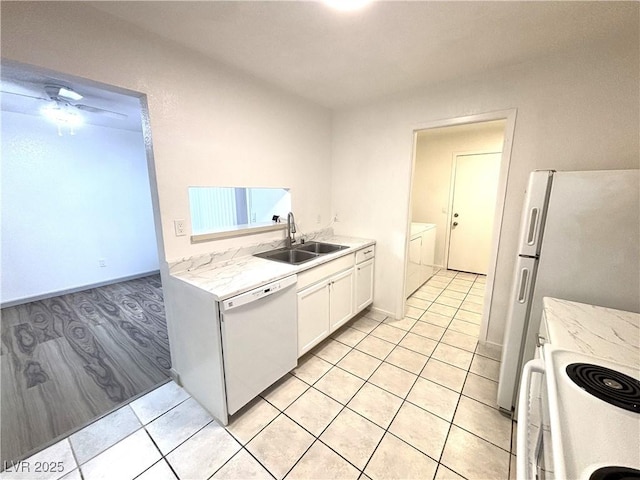 kitchen with washer and clothes dryer, white appliances, sink, light stone countertops, and white cabinetry