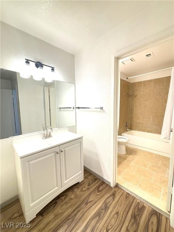 full bathroom with toilet, vanity, wood-type flooring, and tiled shower / bath