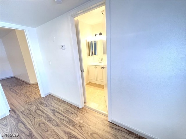 hallway featuring sink and light hardwood / wood-style floors