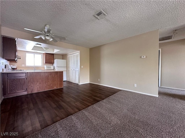 kitchen featuring kitchen peninsula, dark hardwood / wood-style flooring, white appliances, a textured ceiling, and ceiling fan