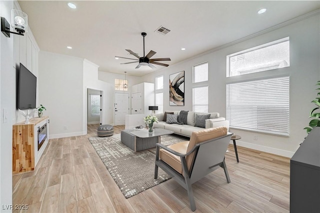 living room featuring light wood-type flooring, ceiling fan, and crown molding