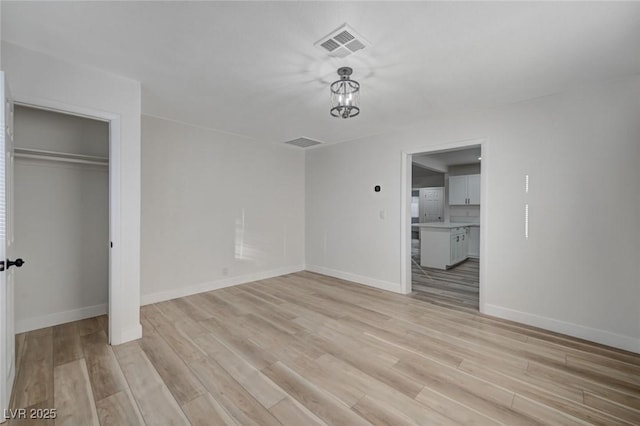 unfurnished bedroom with ensuite bath, a closet, and light hardwood / wood-style flooring