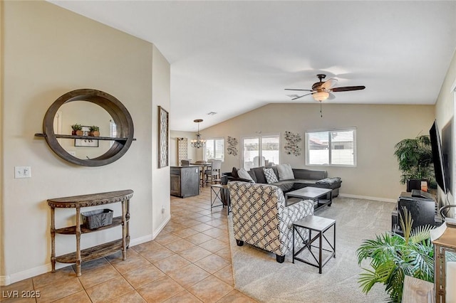 living room with lofted ceiling, light tile patterned flooring, and ceiling fan with notable chandelier