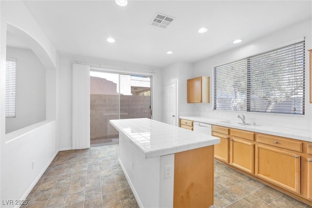 kitchen featuring a center island, tile countertops, white dishwasher, and sink