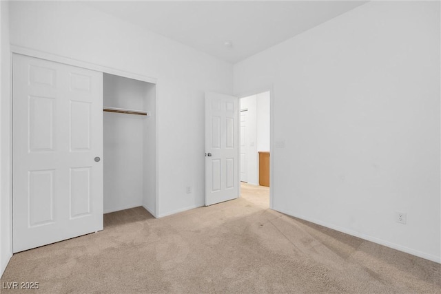 unfurnished bedroom with light carpet and a closet