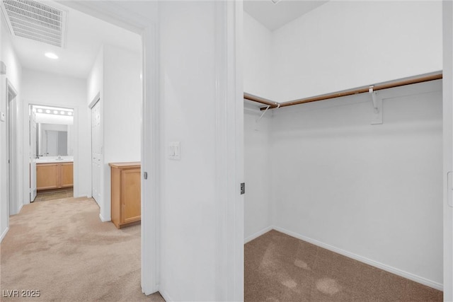 walk in closet featuring light colored carpet