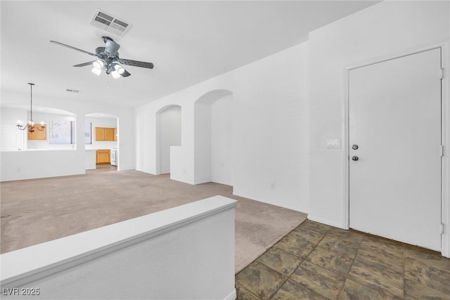 unfurnished living room with ceiling fan with notable chandelier