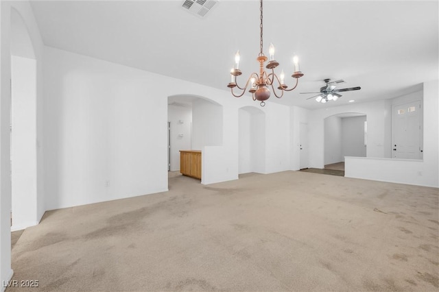 carpeted empty room featuring ceiling fan with notable chandelier